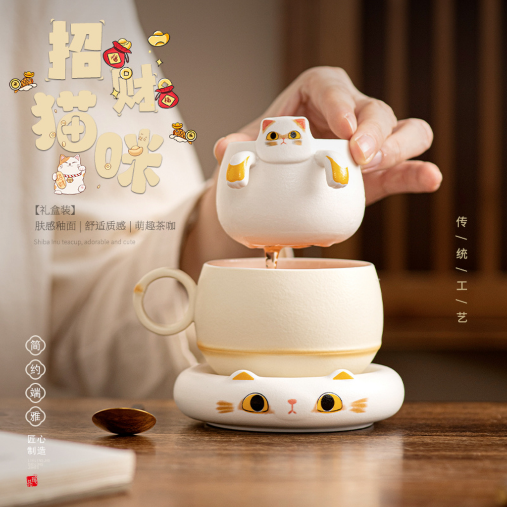 Ceramic cat-shaped mug warmer on a wooden surface with a hand holding a cup.