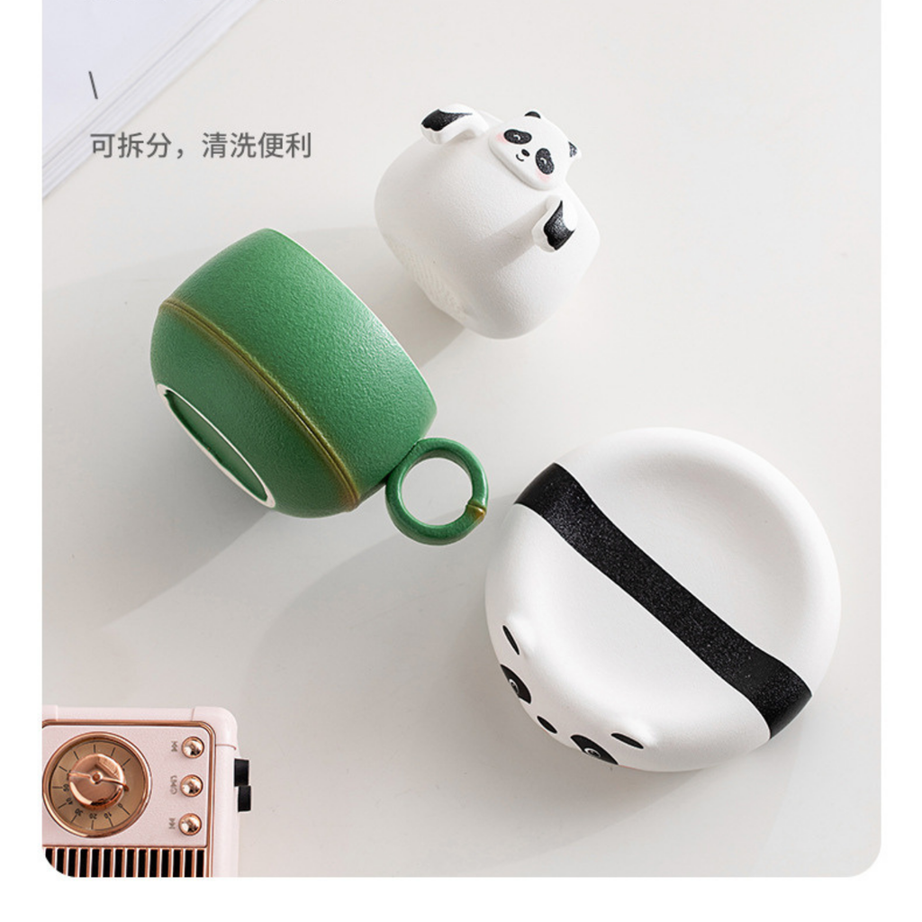 Two panda-shaped ceramic cups, one green and one white with black accents, on a light gray background.