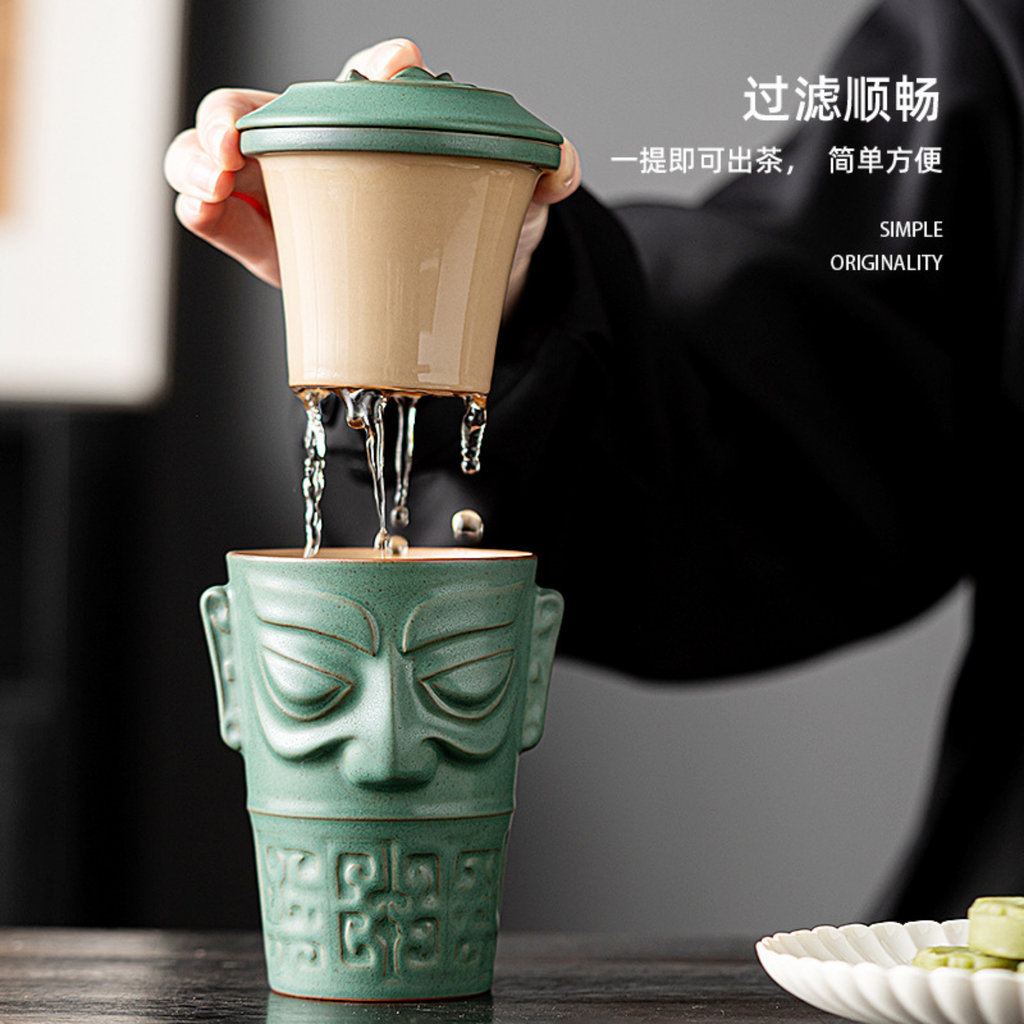 Ceramic tea infuser with face design being used to pour tea.