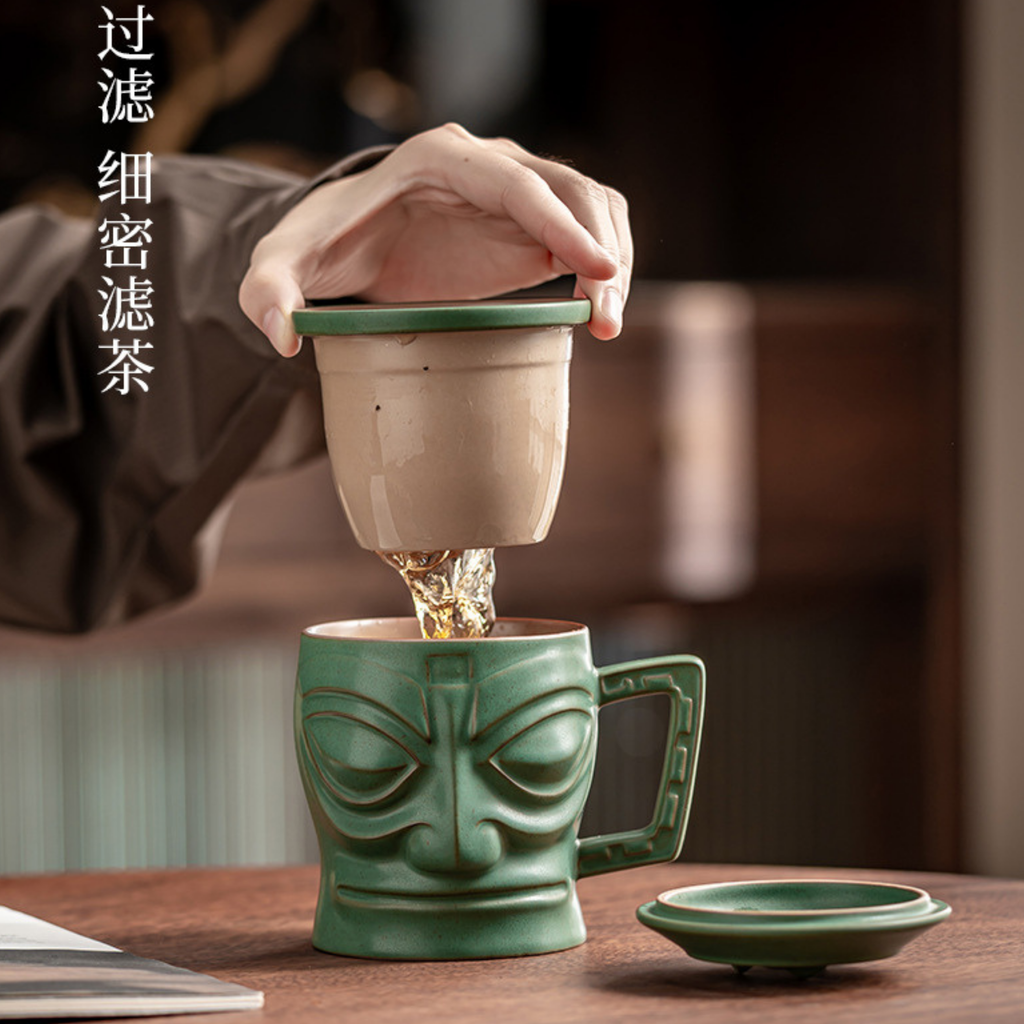 Green ceramic mug with face design being filled with tea, on a wooden table.