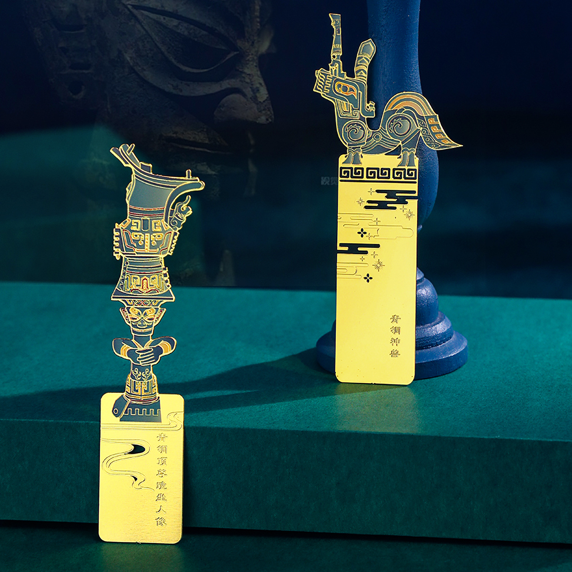 Two decorative items with intricate designs on a dark green surface